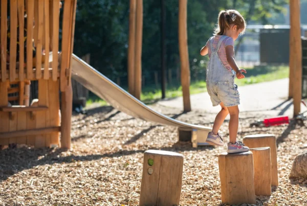 Afbeelding van spelend kind in speeltuin met houten speeltoestellen | Kindcentrum T Veer