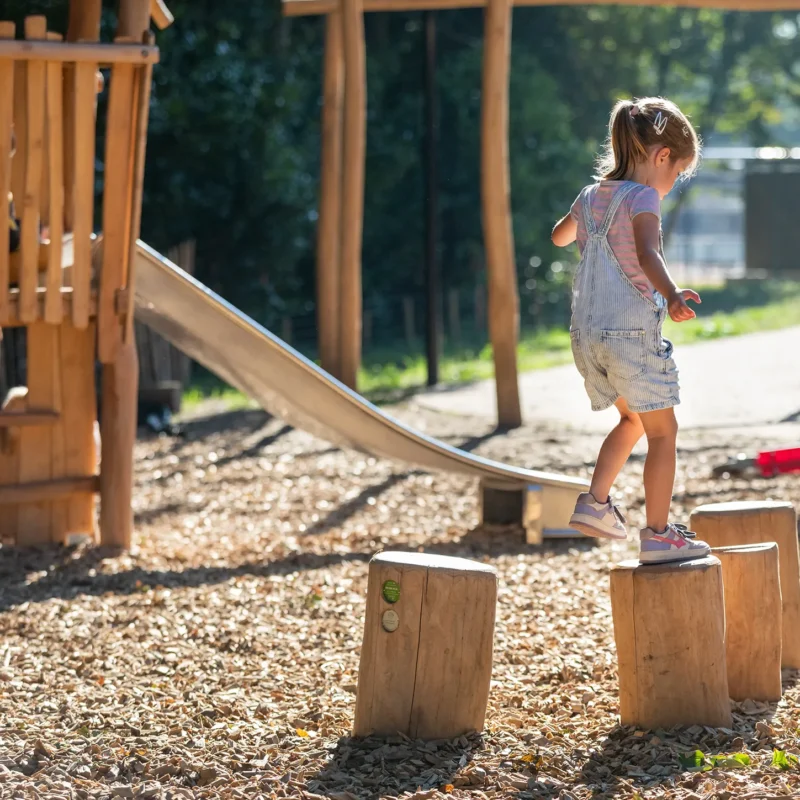Afbeelding van spelend kind in speeltuin met houten speeltoestellen | Kindcentrum T Veer
